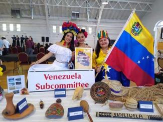 Venezuelan woman stand with flag at table